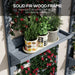 Grey wooden wall-mounted plant stand with trellis holding three patterned cream pots with green plants and red flowers