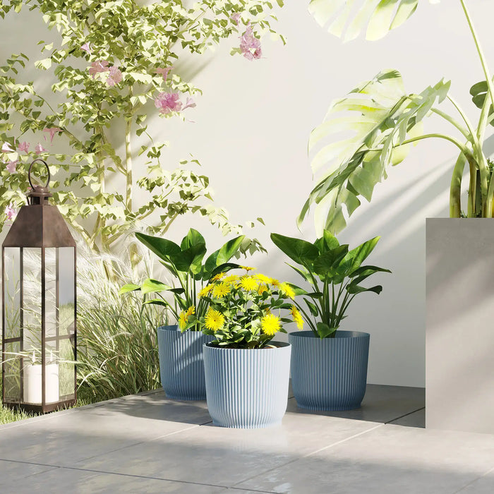 Set of three blue stackable plastic plant pots with green and yellow flowering plants on outdoor patio