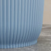 Close-up of textured light blue plastic stackable planter pot with vertical ridges on concrete surface