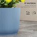 Blue ribbed plastic plant pot with yellow flowers, weather-resistant for indoor and outdoor use