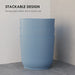 Set of three blue stackable plastic plant pots with ribbed texture in a corner