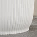 Close-up of white stackable plastic plant pots with vertical ridges on a stone floor