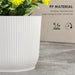 Close-up of white ribbed plastic planter pot with yellow flowers, weather-resistant and durable