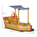 Wooden ship sandbox with adjustable blue canopy, red play steering wheel, storage bench, maritime design, and visible dimensions.