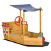 Wooden ship sandbox with adjustable blue canopy, storage bench, red steering wheel, and maritime design.
