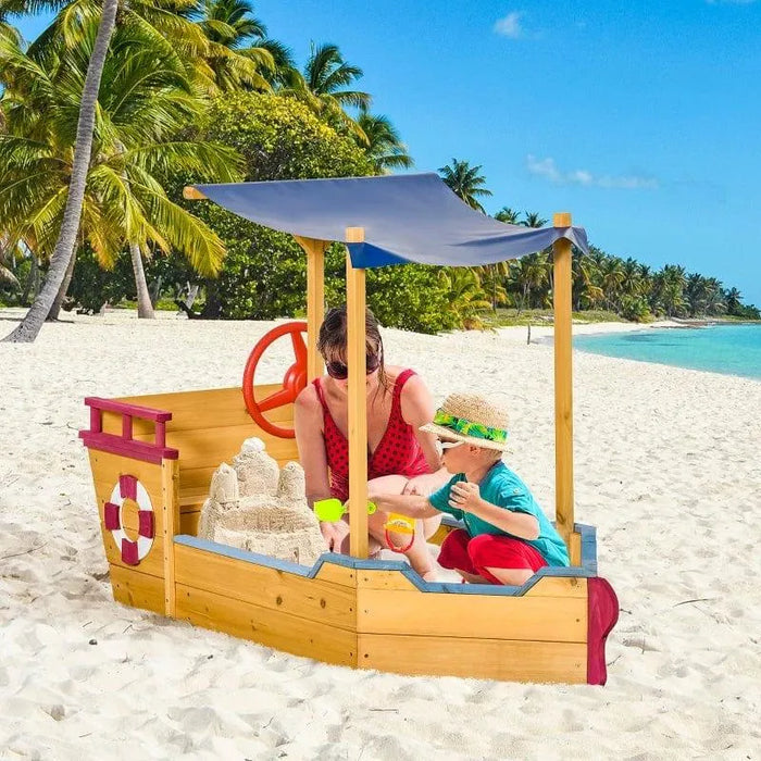 Ship-shaped sandbox with adjustable canopy and storage bench on sunny tropical beach