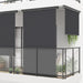 Black side awning installed on modern balcony with glass railing and potted plants