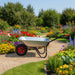Galvanised steel wheelbarrow with a pneumatic tyre on a garden path among colorful flowers