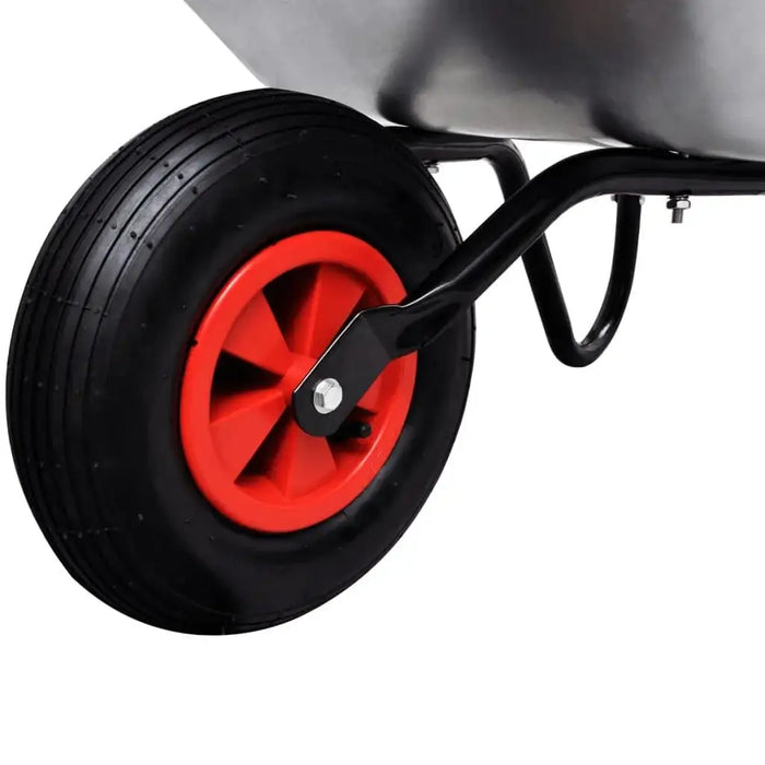 Close-up of single wheelbarrow with red wheel, black frame, and galvanized steel tray