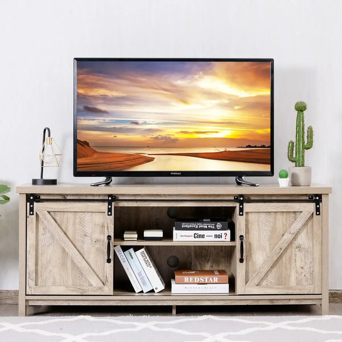 Sliding barn door TV stand with rustic wood finish, holding a 60-inch Samsung TV, books, lamp, and potted cactus