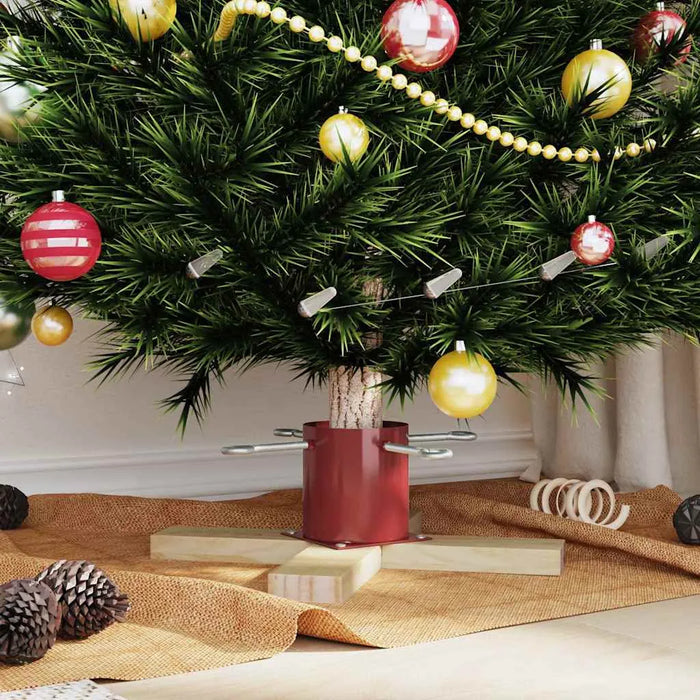 Decorated Christmas tree base with red and gold ornaments, pine cones, and beige fabric on floor