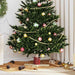 Decorated Christmas tree with red, green, and gold baubles, gold beads, pine cones, and festive indoor setting