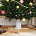 Decorated Christmas tree base with gold and red ornaments, gold bead garland, wooden stand, and pine cones on brown fabric
