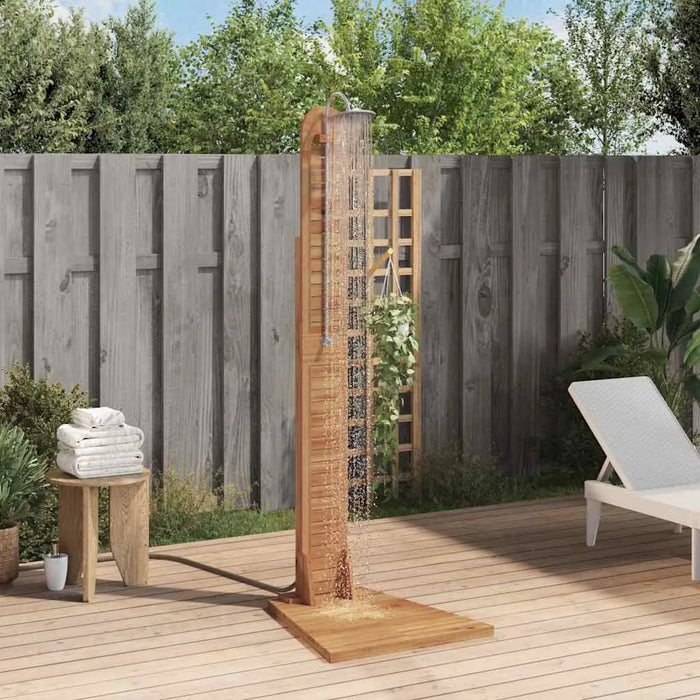 Solid teak outdoor garden shower with stainless steel fixtures on a wooden deck, lounge chair and towels nearby