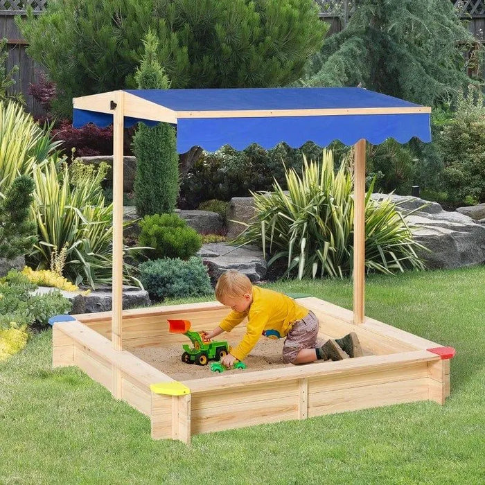 Wooden sandbox with blue canopy, child playing with toy truck in garden