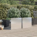 Two silver stainless steel garden planters with green leafy plants on wooden deck patio near black metal fence and chair