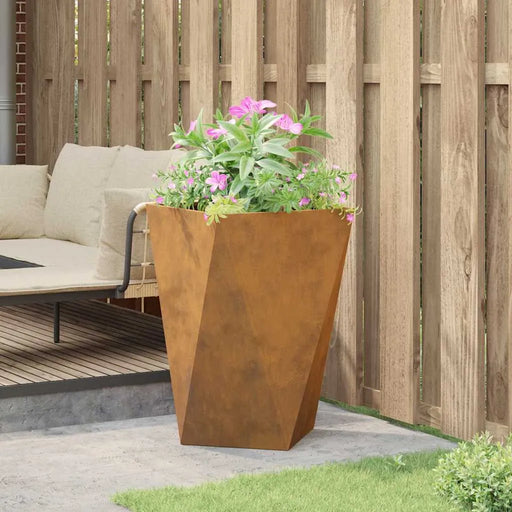 Weathering steel outdoor planter box with pink flowers beside a wooden fence and garden seating