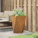 Weathering steel outdoor planter box with pink flowers beside a wooden fence and garden seating
