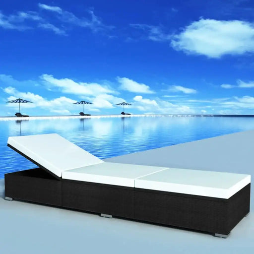 Poly rattan black sun lounger with cream cushion by an infinity pool under blue sky.