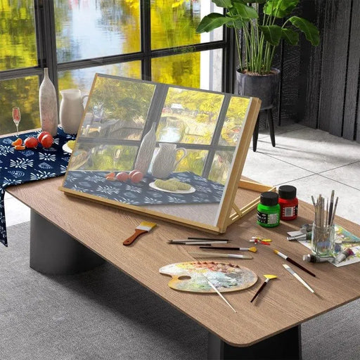 Beechwood desktop table easel with adjustable angle, art supplies, and painting in studio.