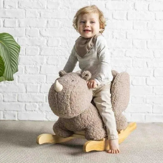 Toddler riding plush taupe rhino rocker with wooden base in bright room