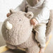 Baby riding taupe plush rhino rocker toy with padded seat and wooden base indoors