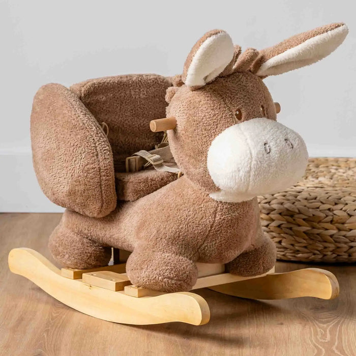 Beige plush donkey rocking toy with safety harness on wooden rockers, soft children's ride-on toy