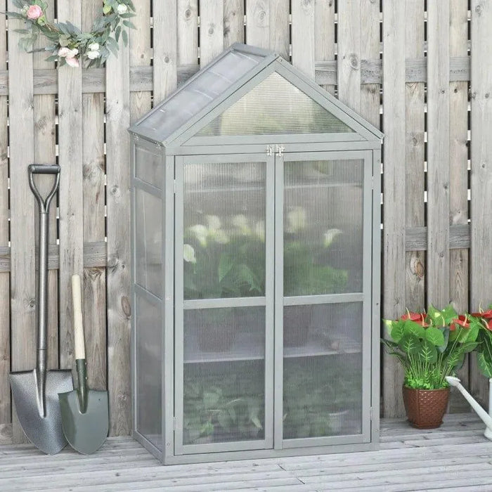 Three-tier grey wooden cold frame greenhouse with adjustable shelves on patio by fence