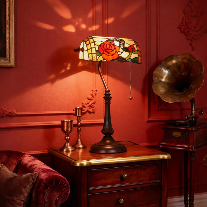 Decorative lamp with stained glass shade on a wooden table against a red wall.