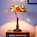 Stained glass lamp with floral design on a wooden table against a soft-focus background