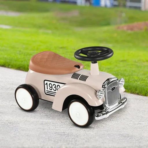 Cream toddler ride-on sliding car with horn, steering wheel, and brown seat outdoors