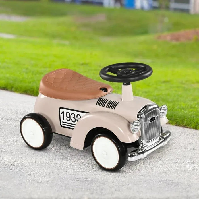 Cream toddler ride-on sliding car with horn, steering wheel, and brown seat outdoors