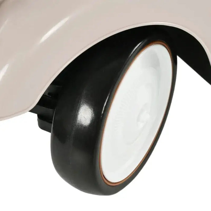 Close-up of black and white wheel on cream toddler ride-on sliding car