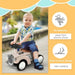 Toddler riding cream sliding car with steering wheel outdoors, foot-to-floor ride-on toy