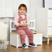 Toddler sitting on white toy storage bench with backrest in modern playroom