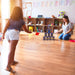 Child playing tin can alley game with numbered cans and beanbags in a classroom setting