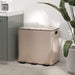Beige trash bin in a room with a plant and cabinet