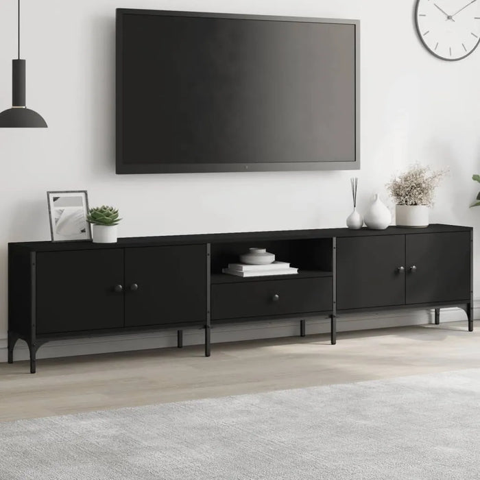 Modern black engineered wood TV cabinet with metal frame, drawers, and decorative plants under mounted flat screen TV
