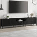 Modern black engineered wood TV cabinet with metal frame, drawers, and decorative plants under mounted flat screen TV