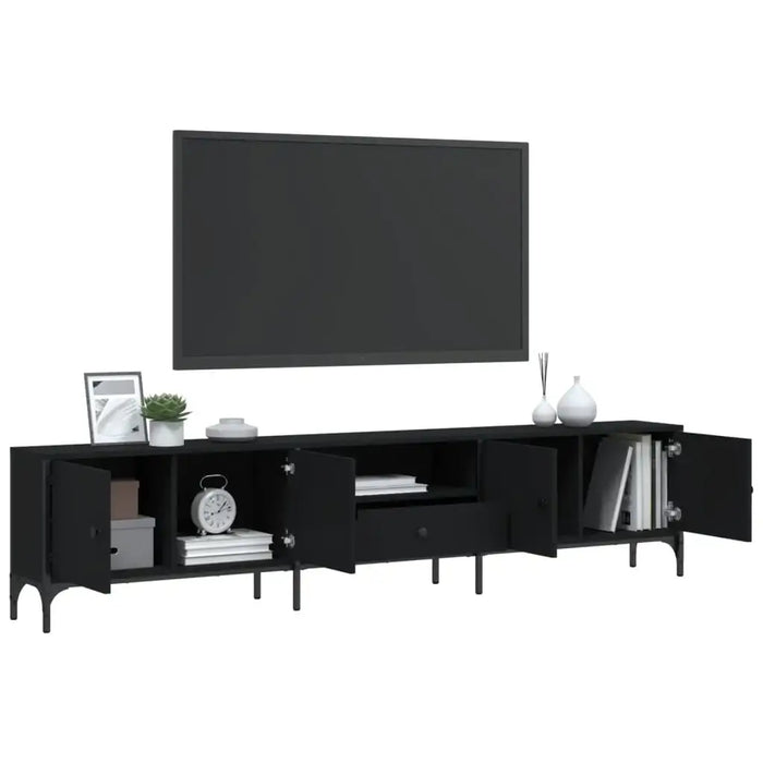 Black engineered wood TV cabinet with metal frame and open doors, holding books, clock, and decor