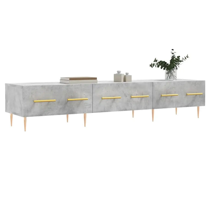 Modern low concrete TV cabinet with gold handles and wooden legs, decorated with books and vase greenery