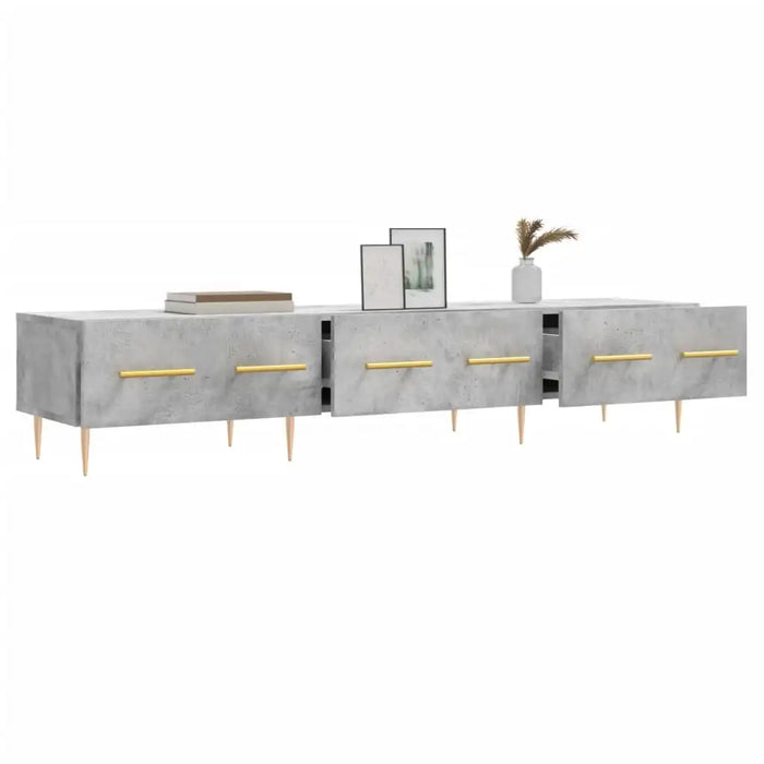 Modern grey concrete TV stand with gold handles, wooden legs, books, framed art, and vase decor