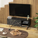 Black TV stand with marble effect and gold accents under wall-mounted flat screen TV in modern living room