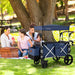 Family sitting on grass next to a blue Costway wagon in a park