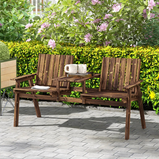 Two-seat carbonised wooden garden bench with central table holding mugs in vibrant outdoor patio setting