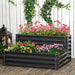 Two-tier dark grey galvanized steel raised garden bed with vibrant pink, red, and purple flowers on wooden deck