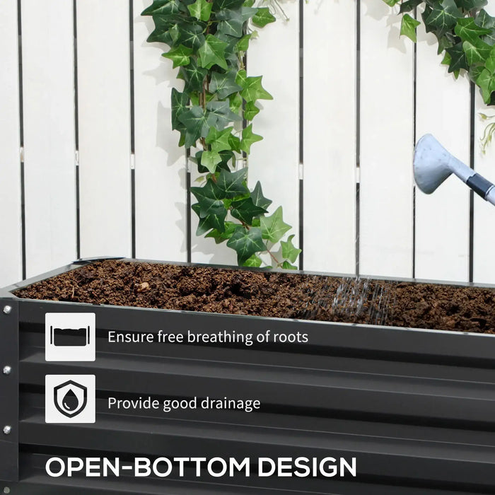 Dark grey two-tier galvanized steel raised garden bed filled with soil being watered, white fence background with green ivy