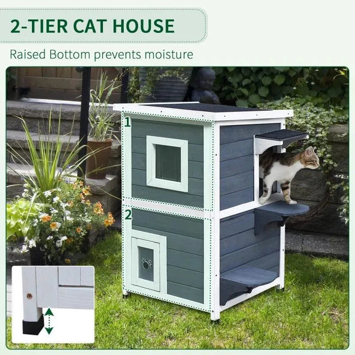 Two-tier outdoor wooden cat house in grey with white trim, cat stepping out, garden background