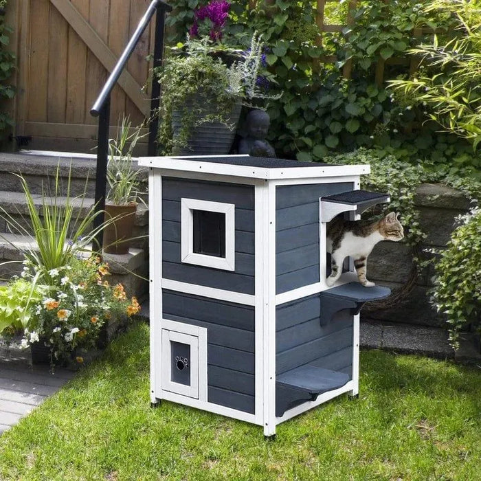 Two-tier grey wooden outdoor cat house with steps, tabby cat, in garden setting
