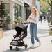 Woman pushing a stroller with a child in it, walking on a sidewalk.